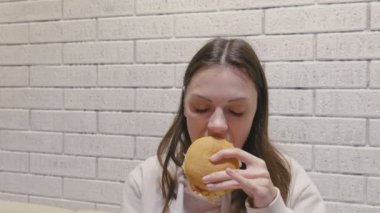 Kadın zevk ve keyif ile hamburger yemek.