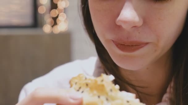 Mulher comendo um hambúrguer com sabor e prazer no café . — Vídeo de Stock