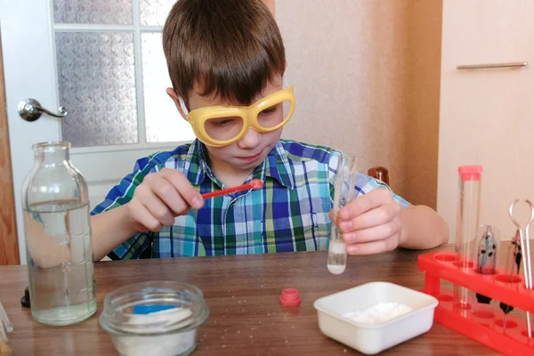 Kísérletek, a kémia otthon. Egy kémcsőbe meglepett fiú kezében gáz megjelenésével kémiai reakció. — Stock Fotó