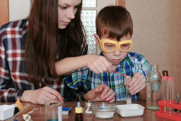 Expériences de chimie à la maison. Maman et son fils font une réaction chimique avec la libération de gaz dans le tube à essai . — Photo