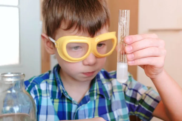 Experimentos de química en casa. Boy está buscando Reacción química con la liberación de gas en un tubo de ensayo en las manos de un chico sorprendido . —  Fotos de Stock