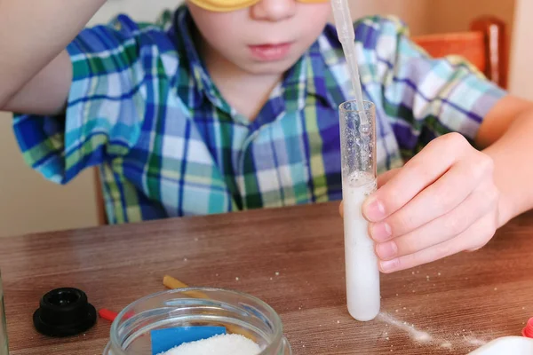 Eksperymenty na chemii w domu. Chłopiec wlać wodę do probówki przy użyciu pipety. — Zdjęcie stockowe
