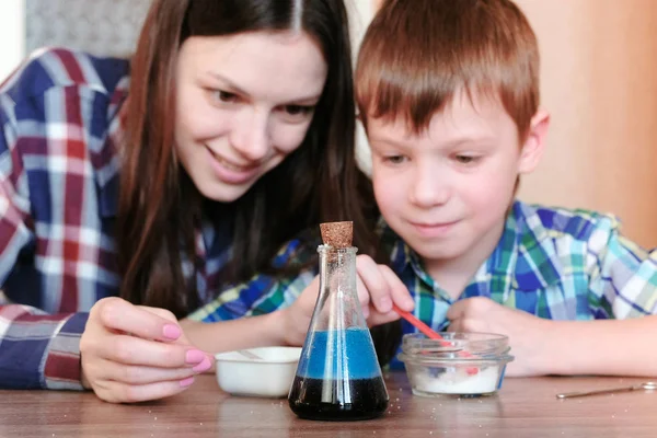 W domu eksperymentów chemicznych. Mama i syn zrobić reakcji chemicznej z uwolnienia gazu w kolbie. — Zdjęcie stockowe