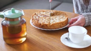 Yakın çekim womans eller ev yapımı elma pasta kesme. Çay ve masanın üzerine çaydanlık