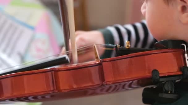Αγόρι 8 ετών μαθαίνει να παίξει βιολί. Παίζει μουσική από τις σημειώσεις. — Αρχείο Βίντεο