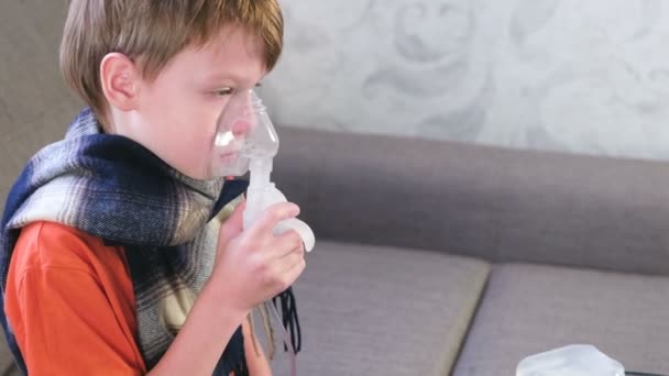 Sjukt söt pojke andas in genom inhalatorn mask. Använda nebulisatorn och inhalator för behandling. — Stockvideo