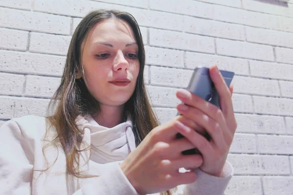 Mulher está digitando uma mensagem no celular sentado e esperando alguém no café . — Fotografia de Stock