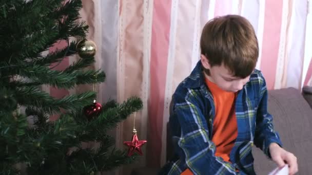 Мальчик украшает елку мячами дома . — стоковое видео