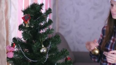 Noel şapkalı kadın evde topları ile Noel ağacı süslemeleri.