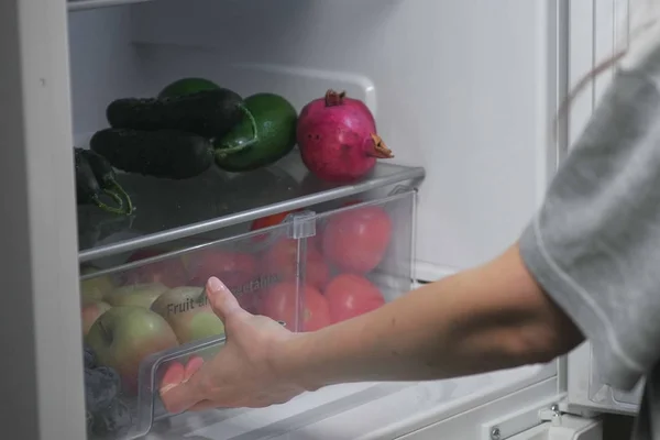 A mulher tira a comida do frigorífico à noite. Mãos fechadas . — Fotografia de Stock