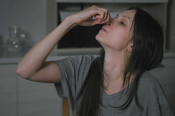 Больной молодой женщины капает носовую каплю к носу на кухне ночью. Лечение ринита дома . — стоковое фото