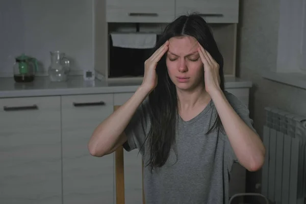Vrouw met hoofdpijn in de keuken bij nacht. Slapeloosheid en depressie. — Stockfoto