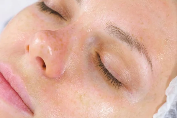 Cara de mujer con una máscara transparente en la cara. Tratamientos faciales en la esteticista . — Foto de Stock