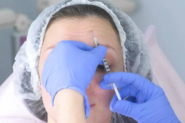 Contorno de cara de plástico. Procedimiento de inyecciones faciales rejuvenecedoras para apretar y alisar las arrugas en la piel de la cara de una hermosa mujer joven en una clínica de cosmetología . — Foto de Stock