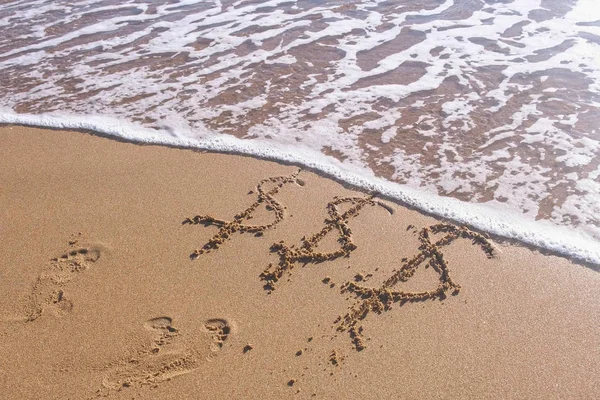 Signos de dólar en la arena del mar. Ondas lavaron la inscripción . —  Fotos de Stock