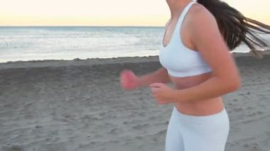 Genç kadın kum plaj, deniz kenarında sonbahar gündoğumu, jogging, yakın çekim bacaklar görünümü yan.