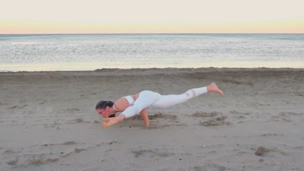 Junge Frau beim Yoga am Sandstrand bei Sonnenaufgang. Gleichgewichtsstellung. — Stockvideo