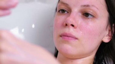 Kadın banyoda yalan yüzünde bir maske koyar. Yüz yakın çekim. Beyaz arka plan.