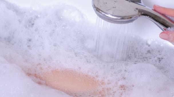 Vrouw is het nemen van een bad met schuim. Ze giet haar lichaam water uit de douche. Schuim close-up. — Stockvideo