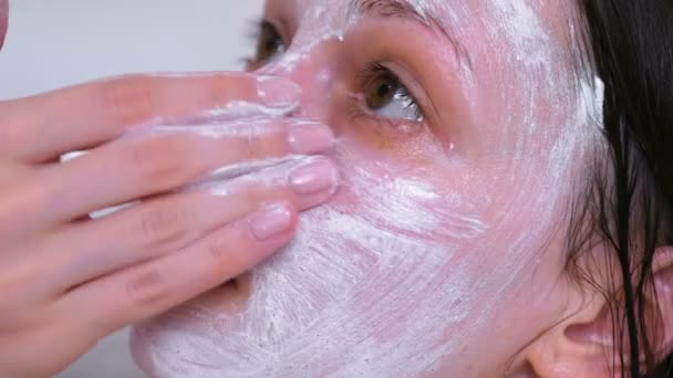美しいブルネットの女性は、自宅の浴室で横になっている顔にマスクを置きます。顔のクローズ アップ. — ストック動画