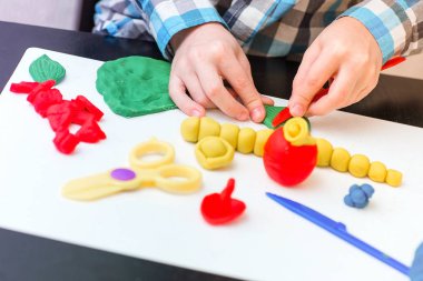 Küçük çocuk hamuru evde, el yakın çekim sculpts. Plastik bıçak ve makas.