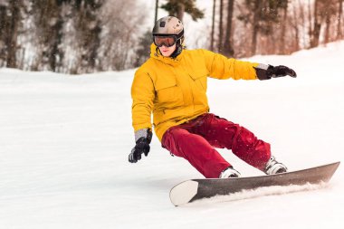Erkek snowboard slaytlardan kış günü dağda orman arka plan üzerinde.