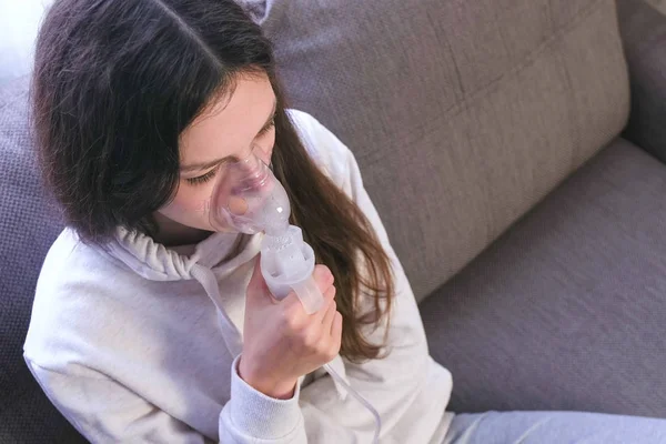 Nebulizatör ve astım tedavisi için kullanın. Genç kadın kanepede oturan inhaler maskesi aracılığıyla teneffüs edilmesi. — Stok fotoğraf