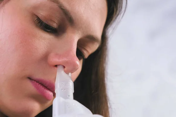 Vernebler und Inhalator für die Behandlung verwenden. junge Frau inhaliert durch Inhalationsdüse für Nase. Gesicht aus nächster Nähe. — Stockfoto