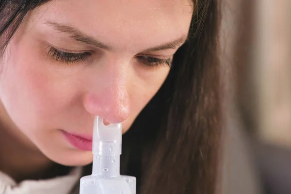 Use nebulizador e inalador para o tratamento. Mulher jovem inalando através do bocal do inalador para o nariz. Cara de perto . — Fotografia de Stock
