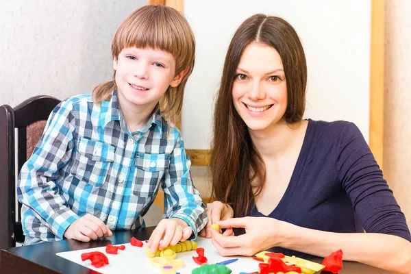 Aranyos fiú és édesanyja színes játék-tészta együtt játszani. — Stock Fotó