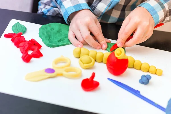 Küçük çocuk hamuru evde, el yakın çekim sculpts. Plastik bıçak ve makas.
