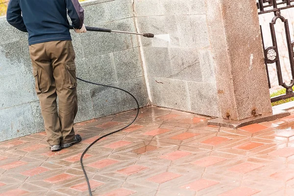 建設労働者は、ホースの水が通りを清掃します。通りで認識できない男. — ストック写真