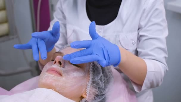 Schoonheidsspecialiste verwijdert en rolt een masker van dames gezicht. Reiniging gezicht. — Stockvideo