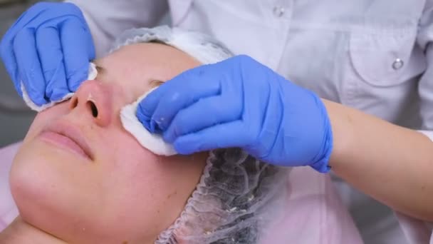 Kosmetolog tvättar kvinnans ansikte med hjälp av bomullsrondeller från mask. Rengöring ansikte. — Stockvideo
