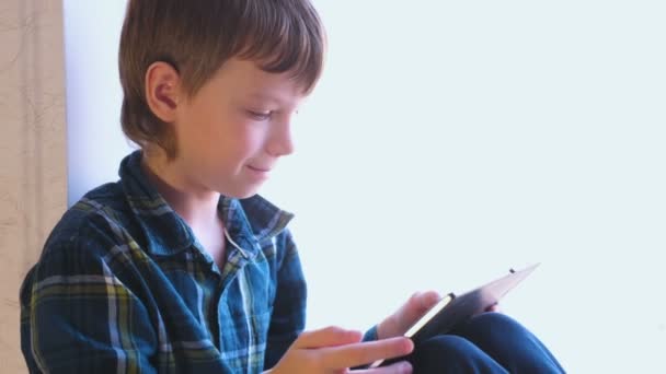 Boy Está Jugando Juegos Tableta Sentado Alféizar Ventana — Vídeos de Stock