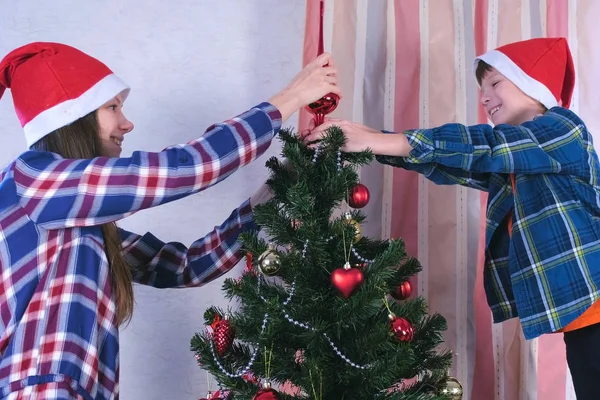 Мать и сын в рождественских шляпах установили шпиль на вершине елки . — стоковое фото