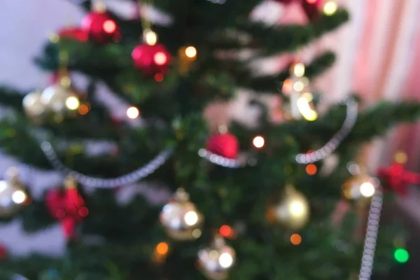Pelotas rojas brillantes y juguetes dorados en las ramas del árbol de Navidad. Guirnalda de Navidad con luces en el árbol de Navidad. Desenfoque . — Foto de Stock