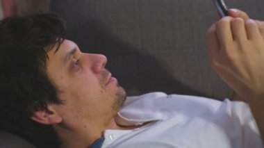 Adam kanepede döşenmesi cep telefonunda görüntülü sohbet görüşmeler.