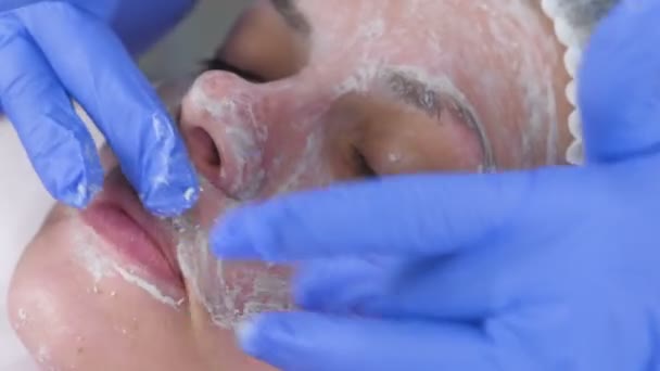Estetista rotola la maschera sui movimenti di massaggio viso delle donne. Trattamento viso cosmetologo. Primo piano . — Video Stock