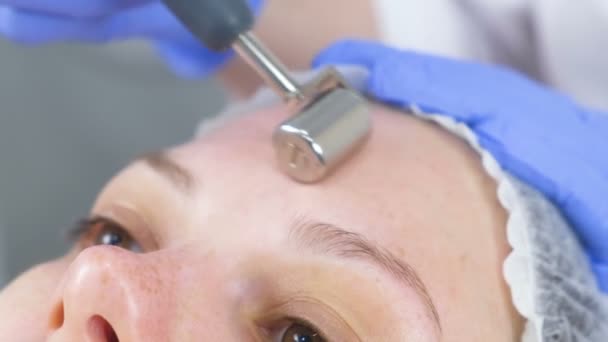 Schoonheidsspecialist maakt een micro-lopende procedure voor het gezicht van een jonge vrouw. Close-up van het voorhoofd. — Stockvideo