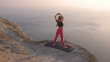 Gün batımında deniz manzaralı dağ germe yoga yaparken kadın güzel manzarasına. Kol germe.
