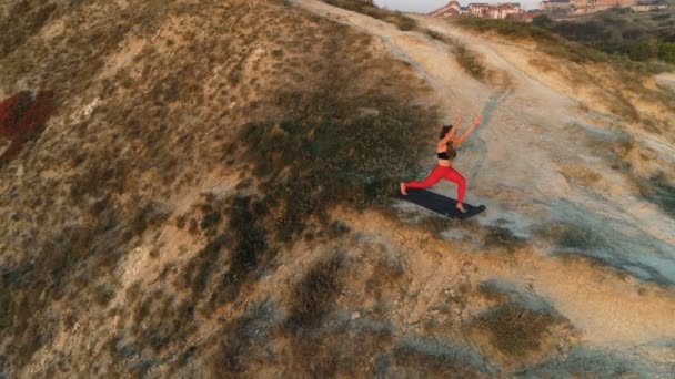 La mujer está haciendo yoga High Lunch Pose en la cima de la montaña al atardecer. Imágenes aéreas hermosas . — Vídeo de stock