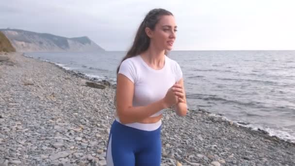女孩正在做运动冲刺, 腿抬起身体弯曲在海上呼吸练习的背景. — 图库视频影像