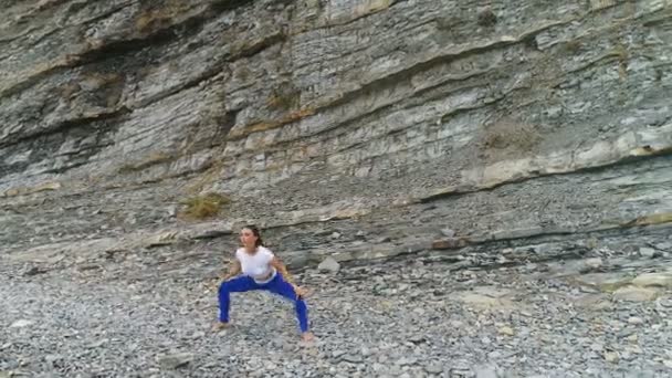 Frau macht Kniebeuge bei Atemübungen auf dem Felsen-Hintergrund. Luftaufnahme schöner Aufnahmen. — Stockvideo