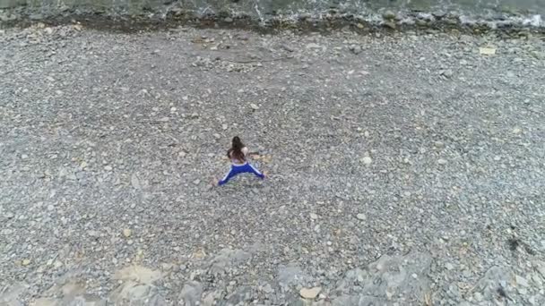 La mujer está haciendo yoga y ejercicios físicos sobre roca y fondo marino. Vista aérea de imágenes hermosas . — Vídeo de stock