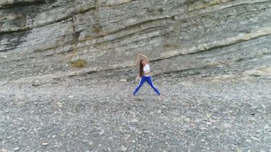 Kadın yoga ve rock ve deniz arka plan üzerinde fiziksel egzersizler yapıyor. Hava güzel görüntüleri görünümü.