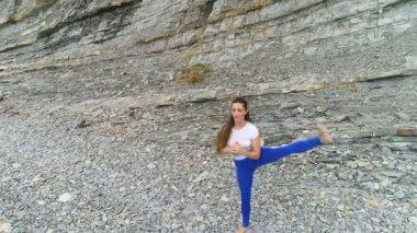 Kadın yoga ve kaya zemin üzerine bacak için fiziksel egzersizler yapıyor. Hava güzel görüntüleri görünümü.