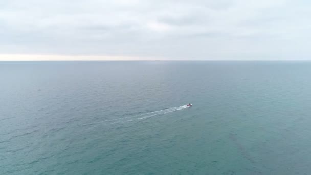 Letecký pohled na motorový člun plující po moři. Zelené moře čisté vody. hory a skály s pobřežní město. — Stock video