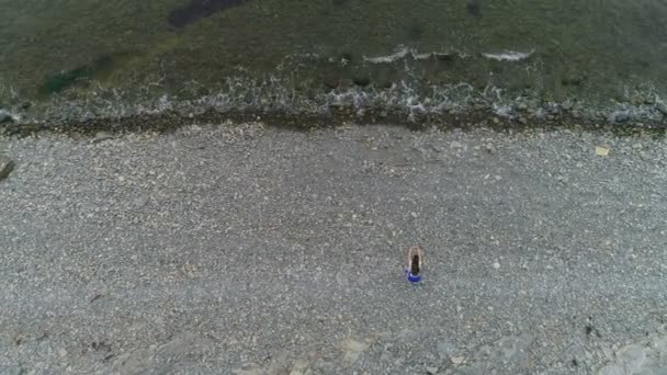 Vrouw doet squats de bodyflex op het stenen strand zee. Luchtfoto mooi beeldmateriaal bovenaanzicht. — Stockvideo