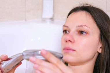 Kadın bir duş alıyor. Depresyon kırmızı gözlü ağlıyor.